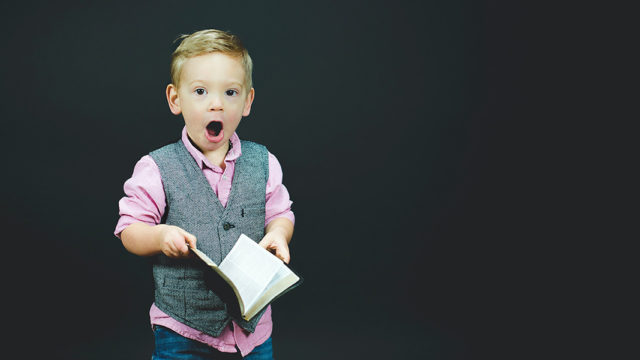 boy with surprised expressing holding book