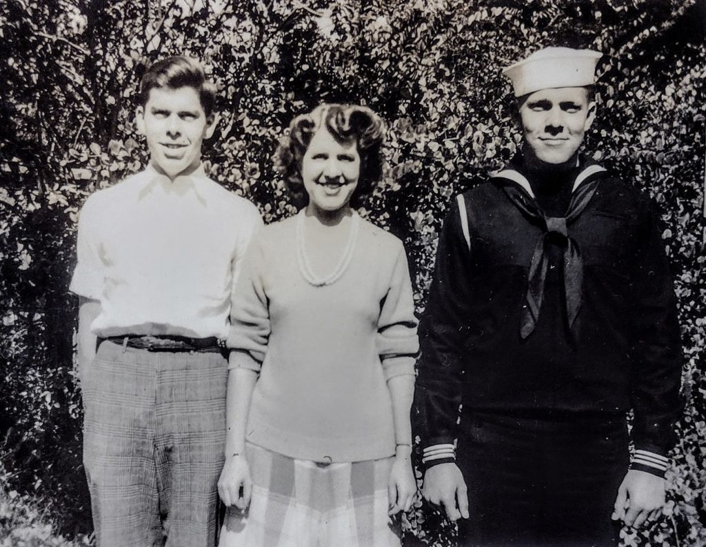 Three people standing in the strong sunlight, facing the camera; Alton Hall, on the right, is wearing a brand new Navy uniform