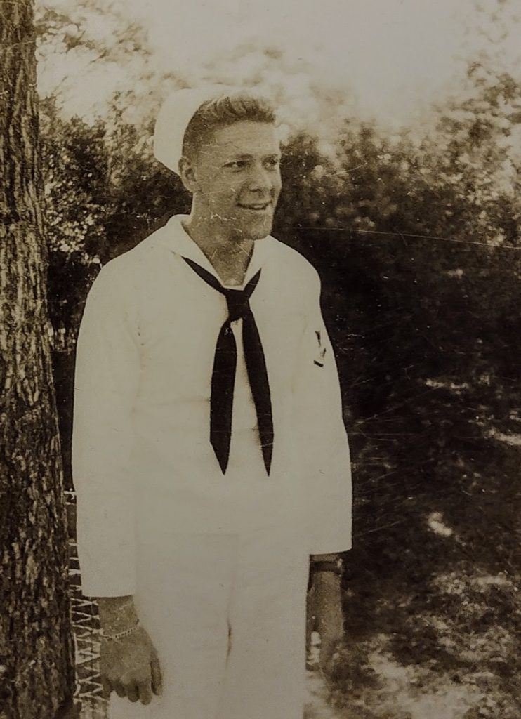 Alton Hall standing alone, in a different Navy uniform; he is much thinner, and his sleeves are too short for his arms