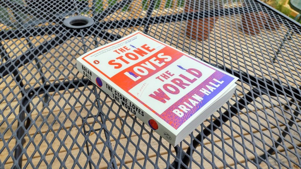 New paperback edition of The Stone Loves the World lying on a patio table