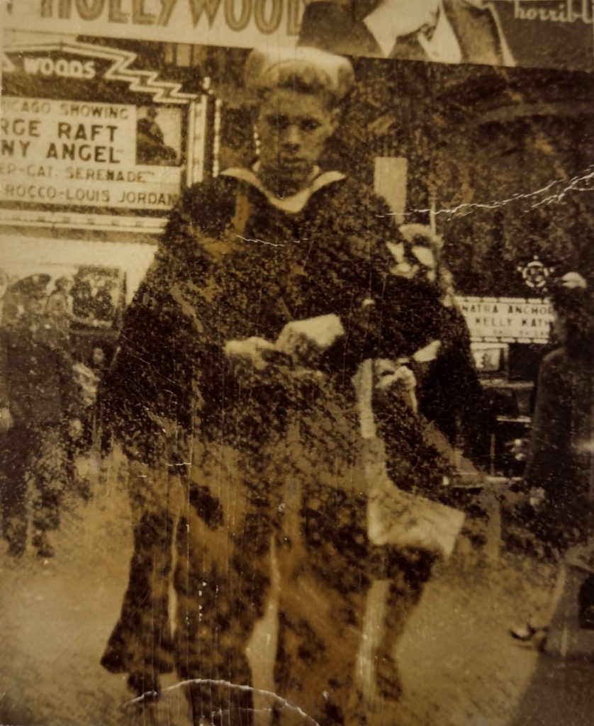 Sun-damaged old photograph of Louis Alton Hall in Navy seaman's uniform on a Chicago street in 1946, counting change in his palm